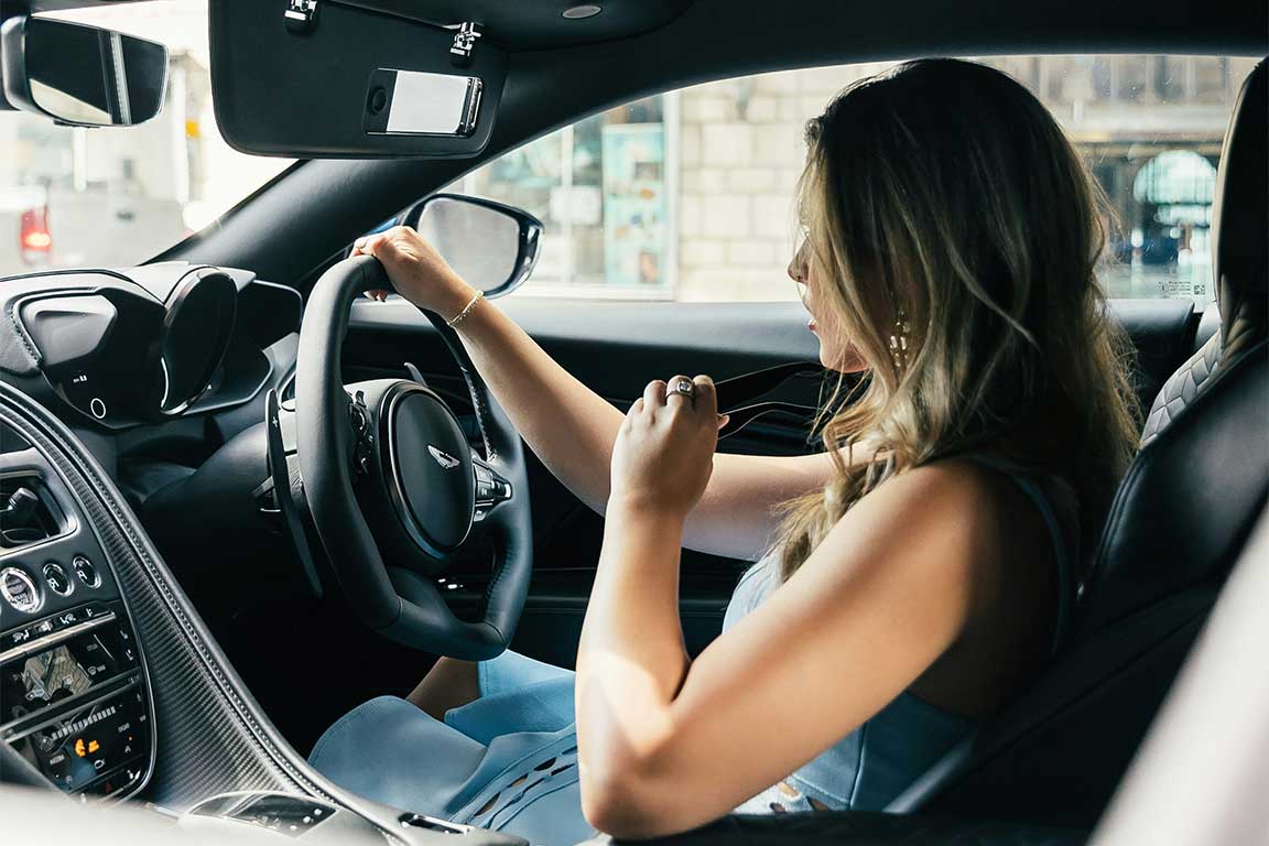 Woman driving an Aston Martin.